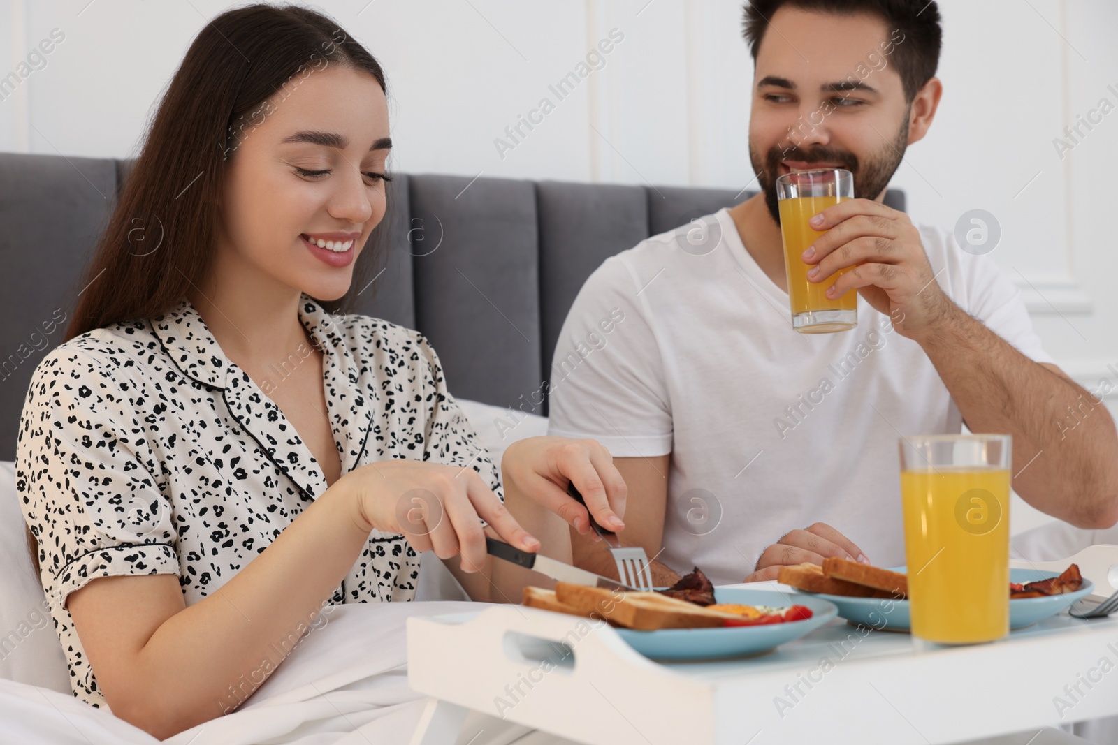 Photo of Happy couple having breakfast on bed at home