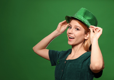 Young woman in green outfit on color background. St. Patrick's Day celebration