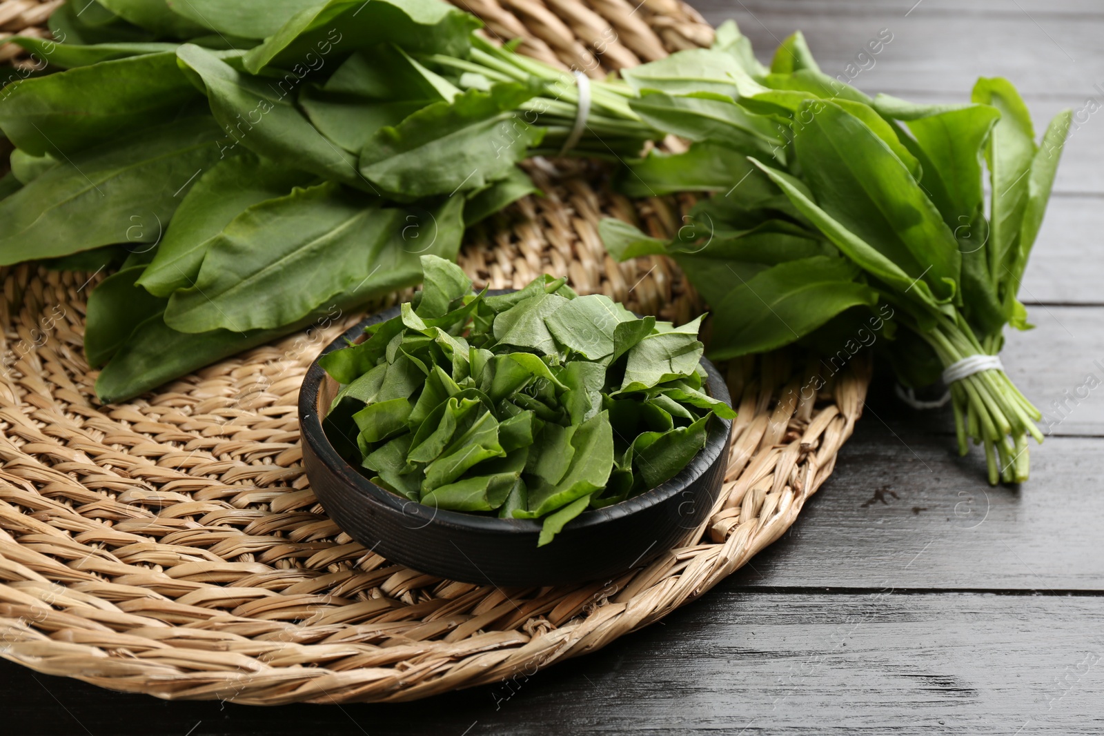 Photo of Fresh green sorrel leaves on black wooden table, closeup