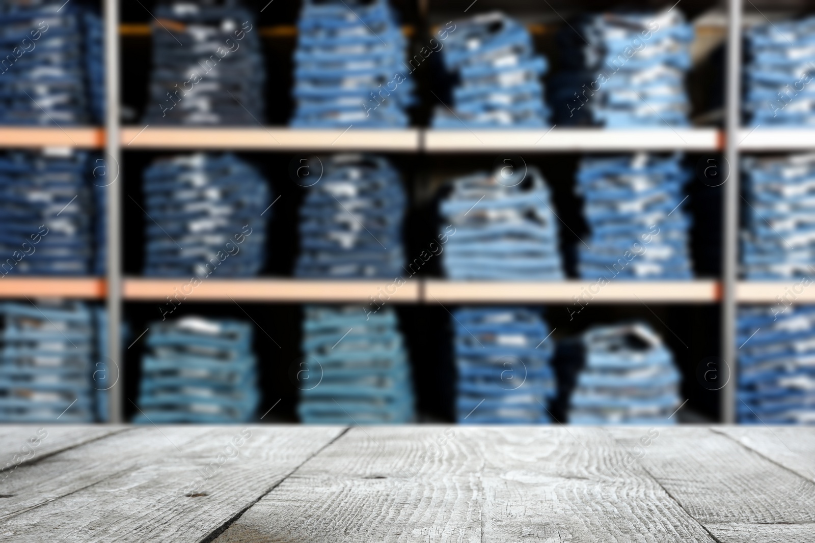 Image of Empty wooden table and blurred view of shelves with jeans in clothes shop