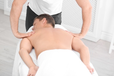 Photo of Relaxed man receiving back massage in wellness center