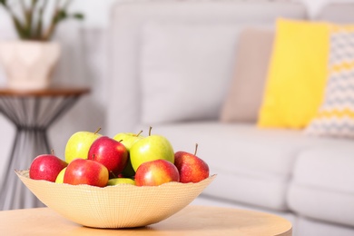 Photo of Bowl with different sweet apples on table in living room, space for text