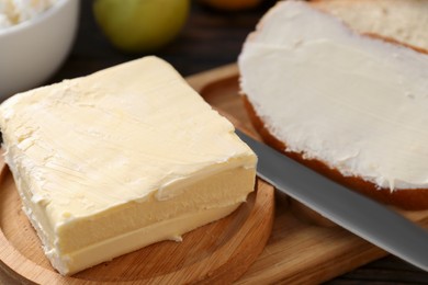 Photo of Tasty homemade butter and bread slices on wooden tray, closeup