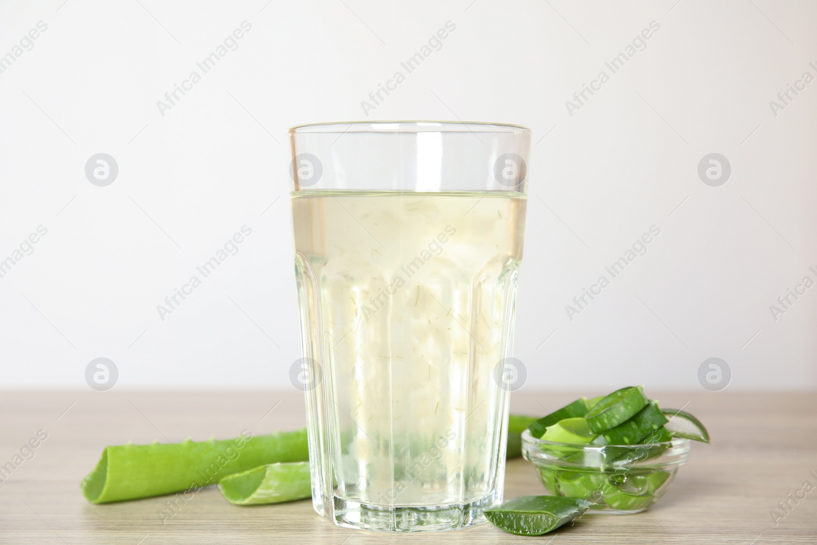 Photo of Fresh aloe drink in glass and leaves on wooden table