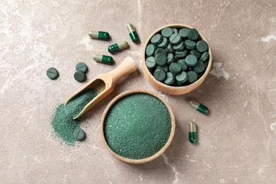 Photo of Spirulina pills and powder on color background, flat lay