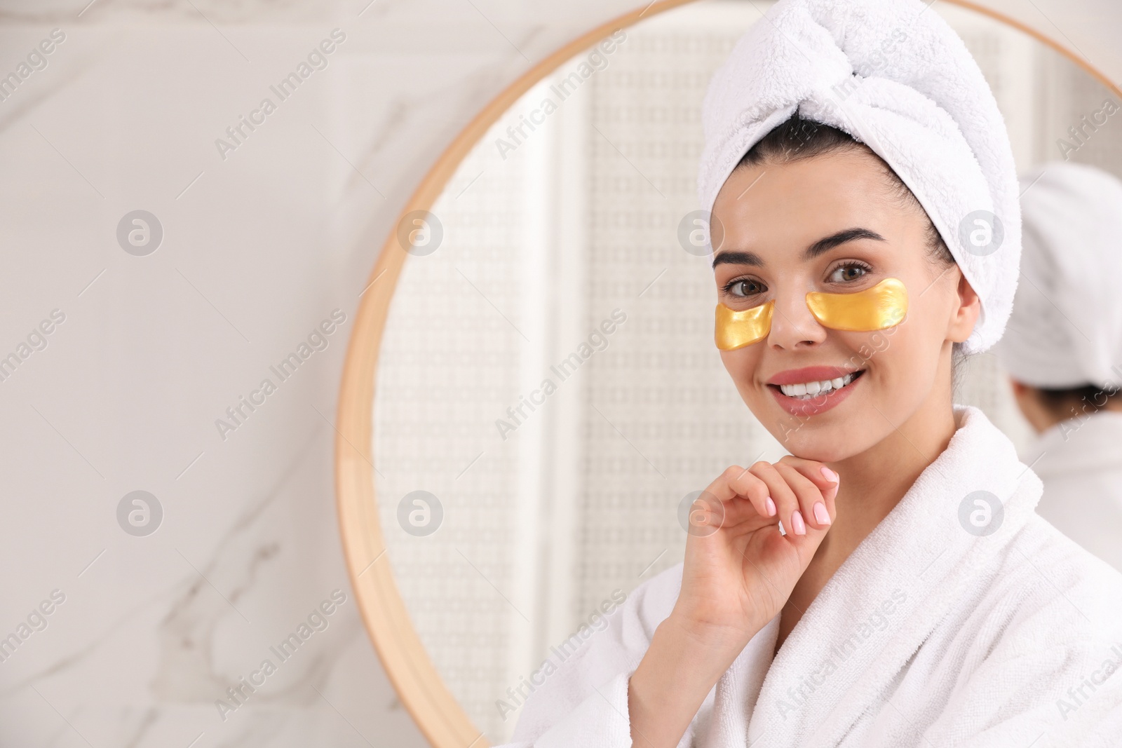 Photo of Beautiful young woman with under eye patches at home, space for text