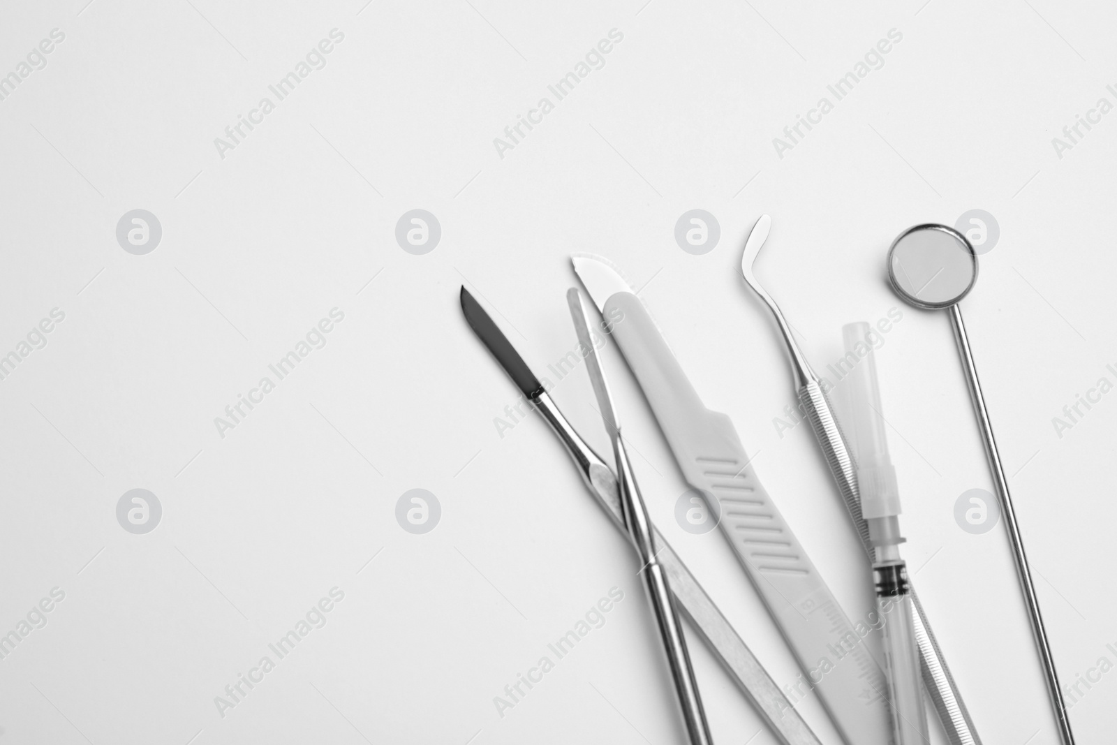 Photo of Set of different dentist's tools and syringe on light background, flat lay. Space for text