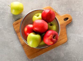 Fresh ripe apples in colander on light grey table, top view