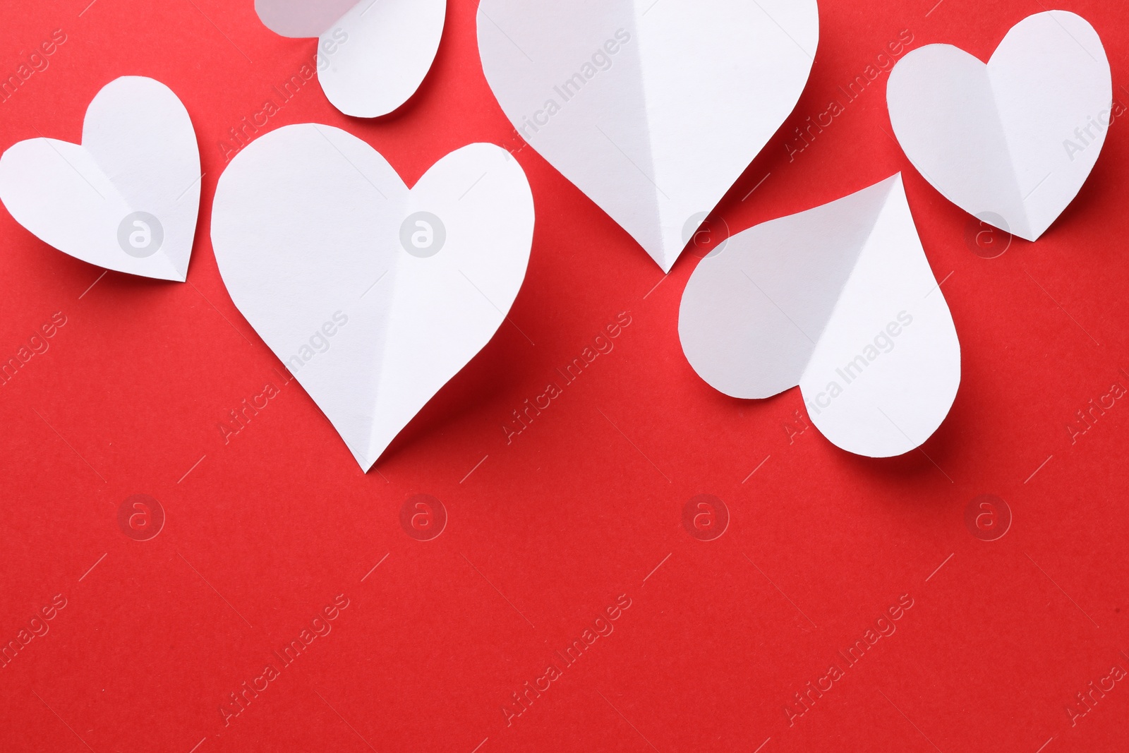Photo of White paper hearts on red background, flat lay. Space for text