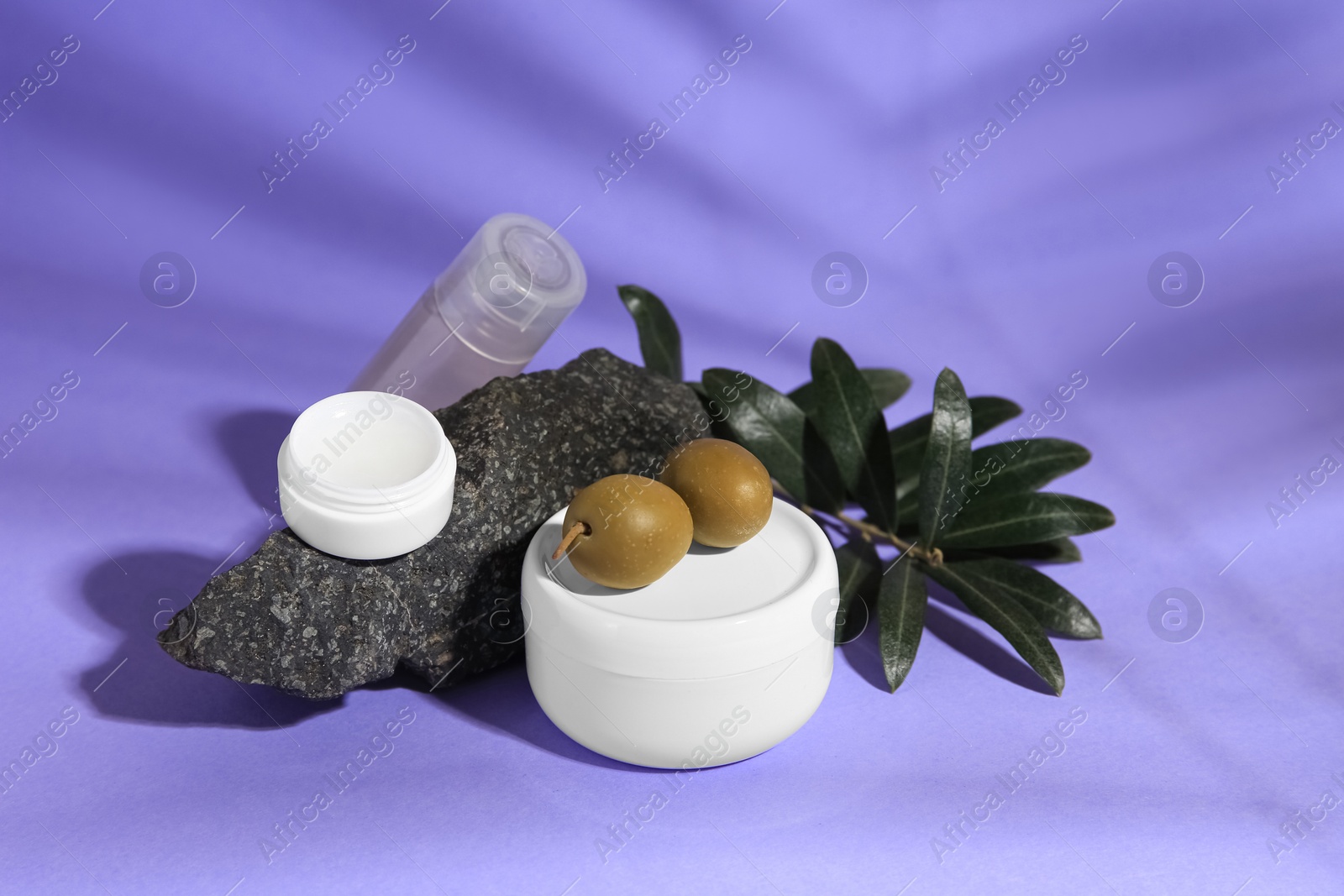 Photo of Cosmetic products and olives on lilac background