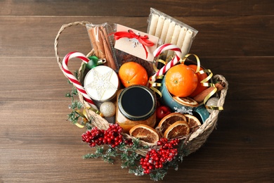 Photo of Wicker basket with gift set and Christmas decor on wooden table, above view