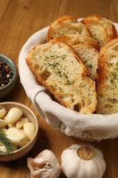 Photo of Tasty baguette with garlic and other spices on wooden table