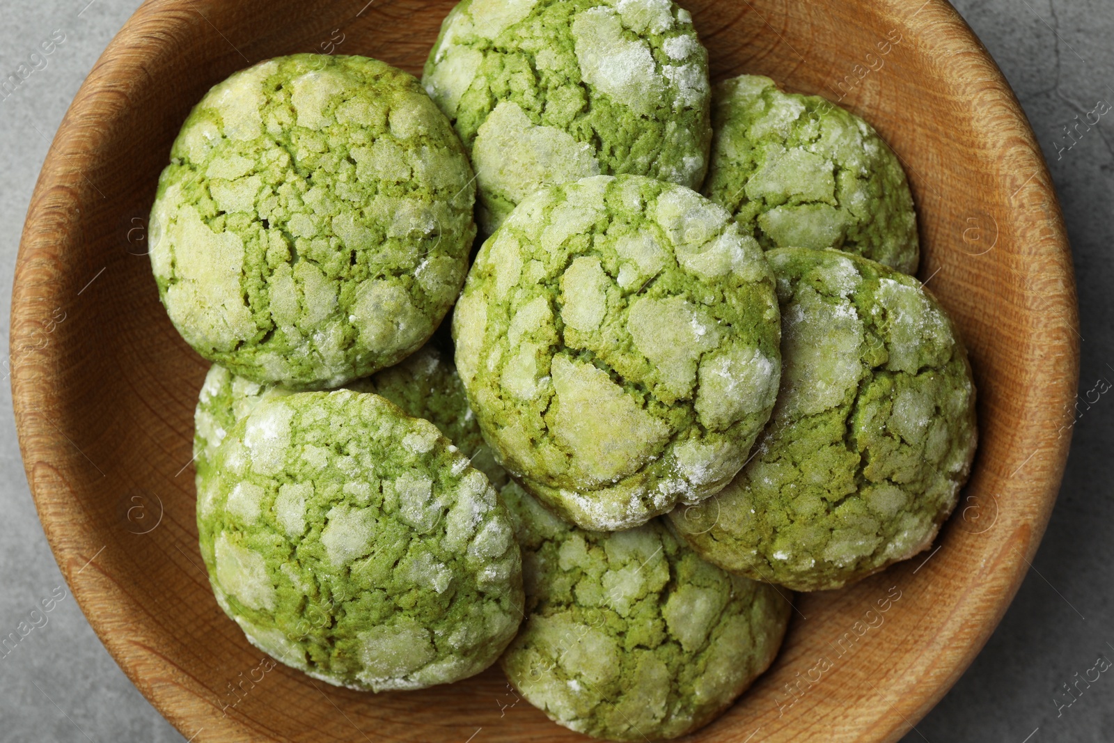 Photo of Bowl with tasty matcha cookies on grey textured table, top view