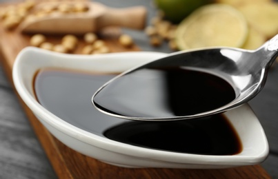 Photo of Spoon with soy sauce over dish, closeup