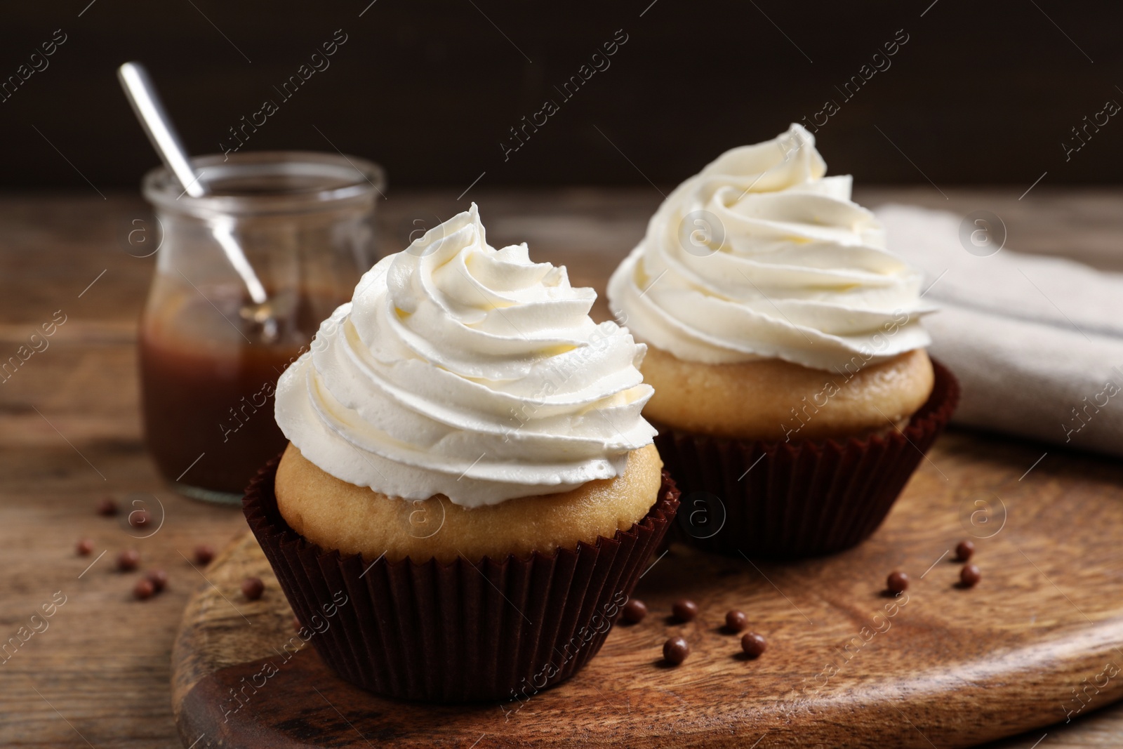 Photo of Delicious cupcakes with cream on wooden table, closeup