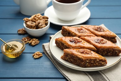 Delicious sweet baklava with walnuts and honey on blue wooden table