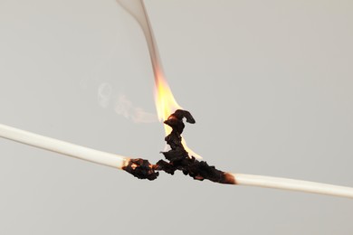 Photo of Inflamed white wire on grey background, closeup. Electrical short circuit