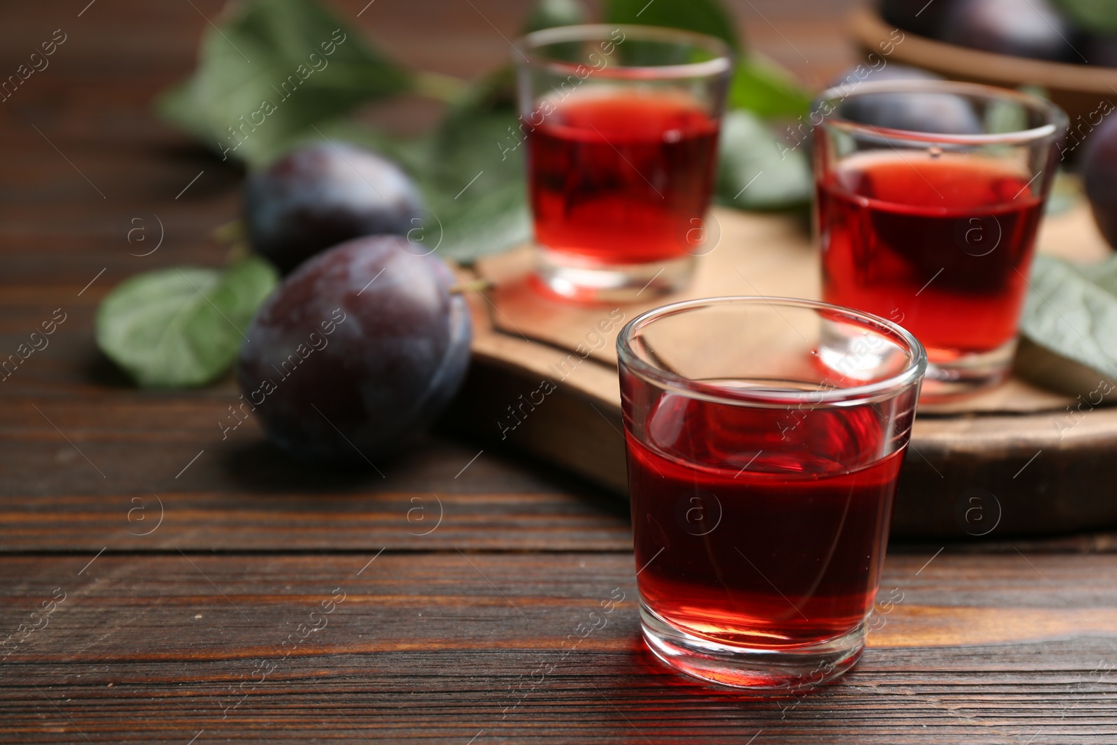 Photo of Delicious plum liquor on wooden table. Homemade strong alcoholic beverage