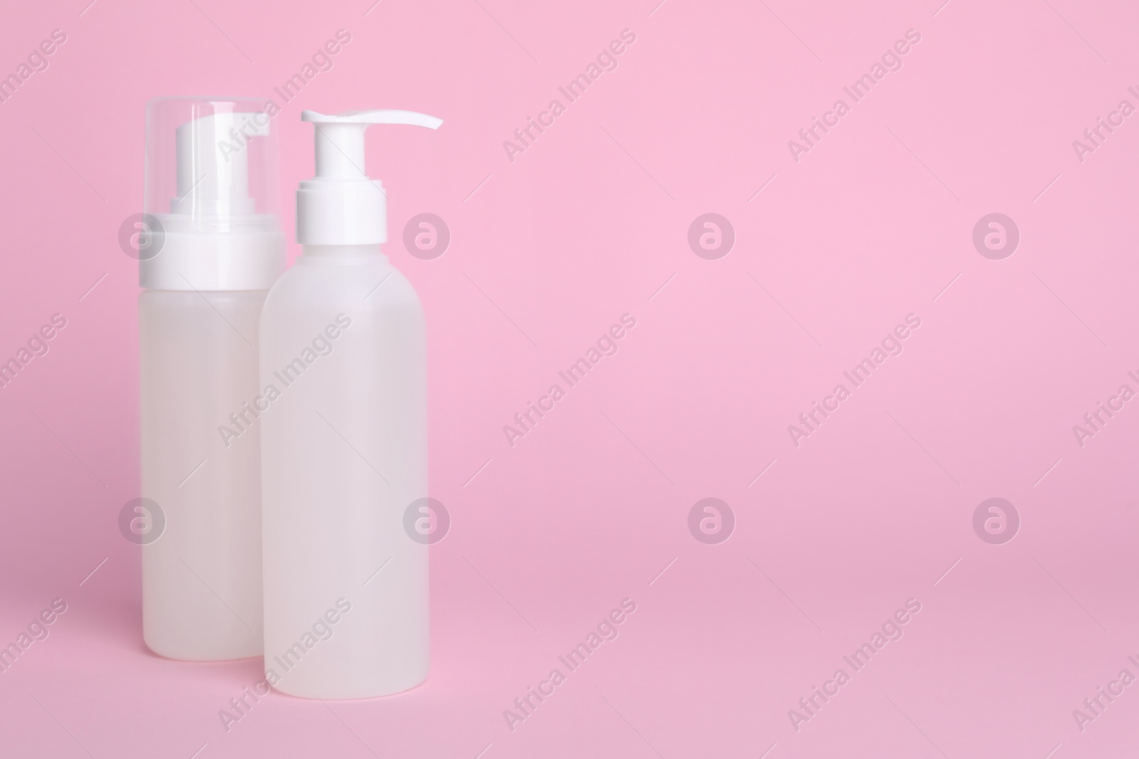 Photo of Different cleansers on pink background, space for text. Cosmetic product