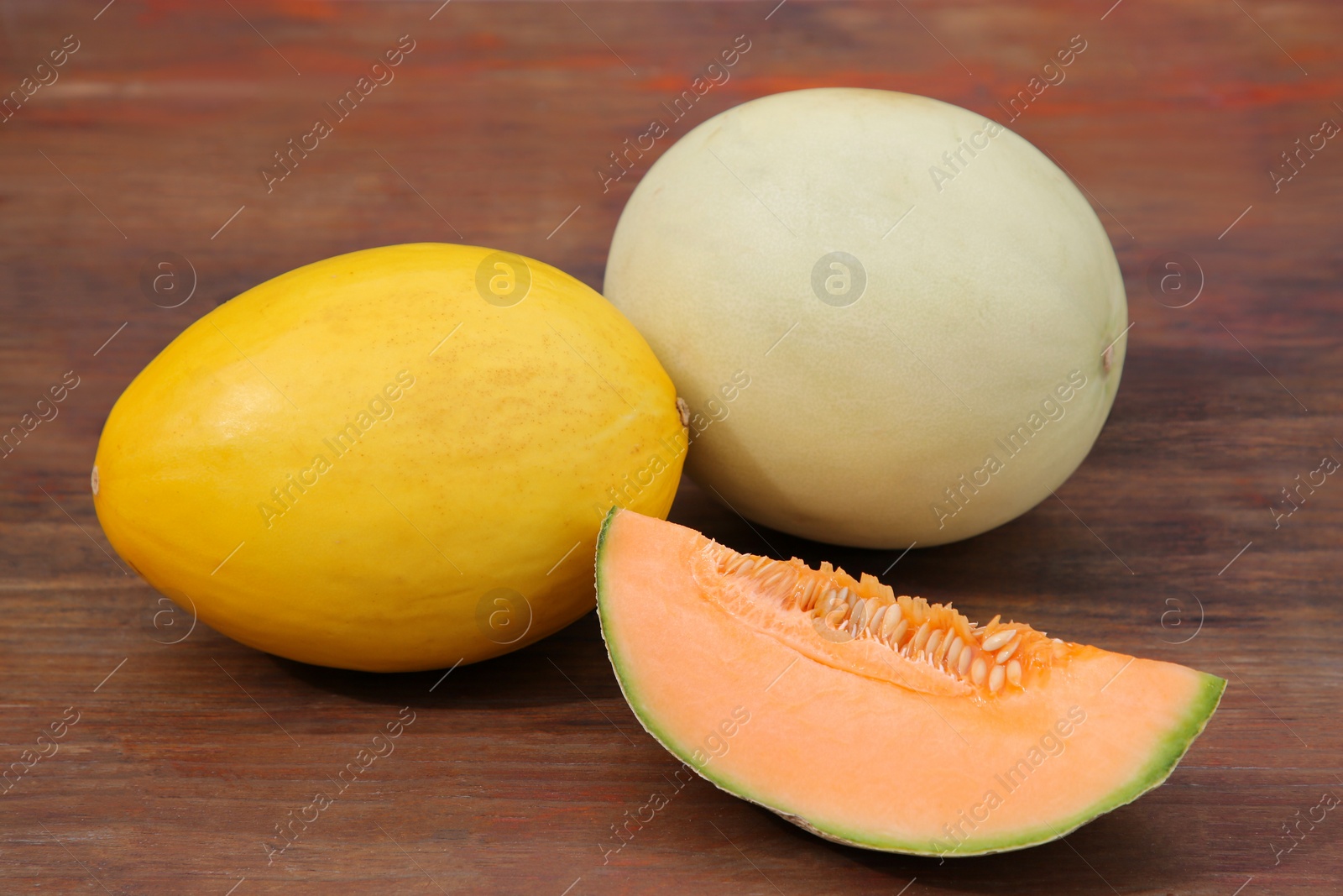 Photo of Whole and cut ripe melons on wooden table