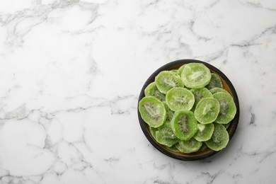 Bowl of dried kiwi on marble background, top view with space for text. Tasty and healthy fruit