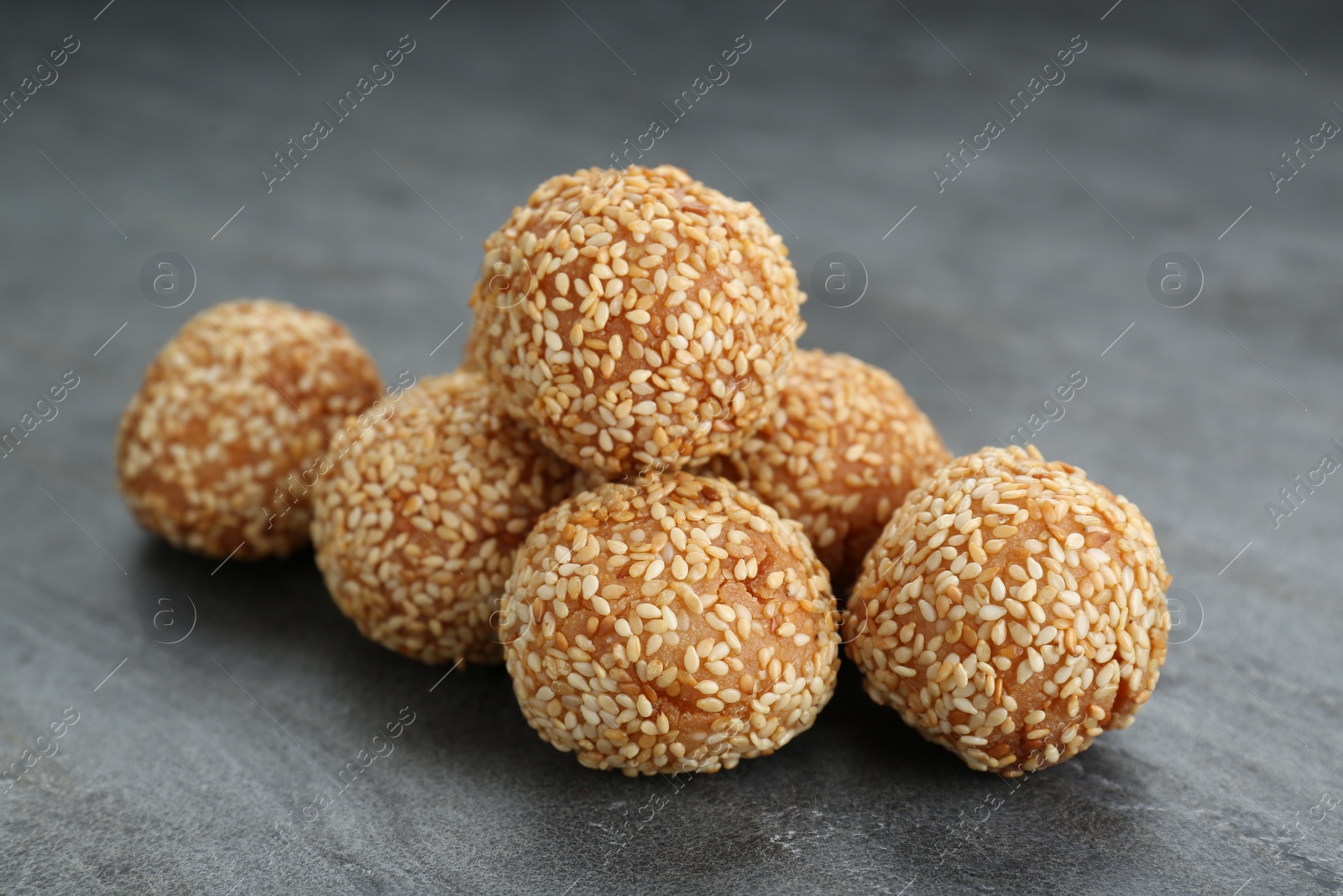 Photo of Many delicious sesame balls on grey table, closeup