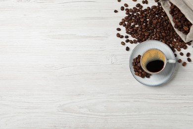 Photo of Cup of aromatic hot coffee and beans on white wooden table, flat lay. Space for text