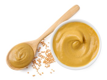 Fresh tasty mustard sauce in bowl, spoon and dry seeds isolated on white