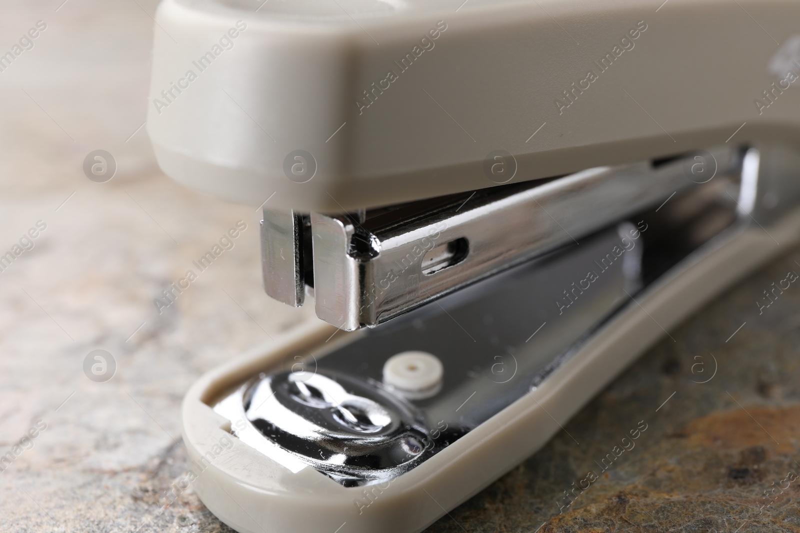 Photo of Beige stapler on stone textured surface, closeup