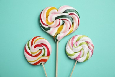 Photo of Sticks with different colorful lollipops on turquoise background, flat lay