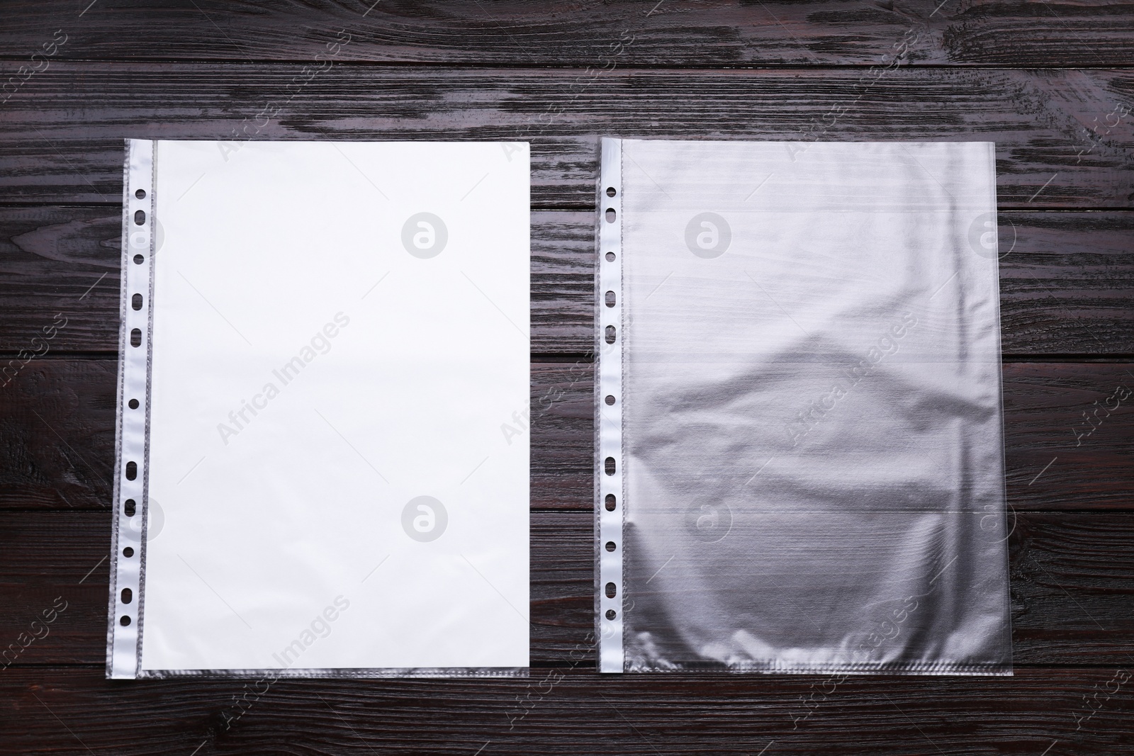 Photo of Punched pockets on brown wooden table, flat lay. Space for text