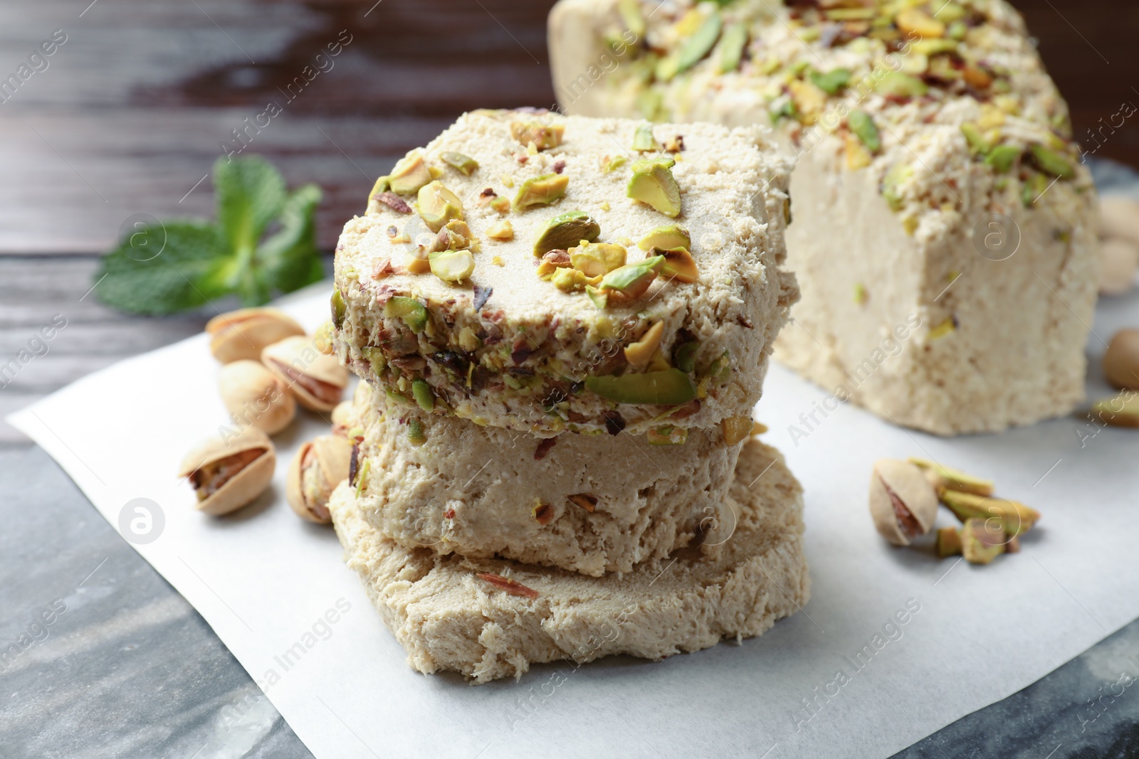 Photo of Pieces of tasty halva with pistachios on table, closeup