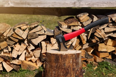 Tree stump with axe and cut firewood outdoors