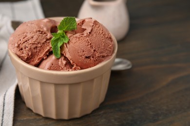 Photo of Bowl of tasty chocolate ice cream on wooden table, closeup. Space for text