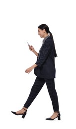 Photo of Young businesswoman using smartphone while walking on white background