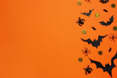 Photo of Flat lay composition with paper bats and spiders on orange background, space for text. Halloween decor