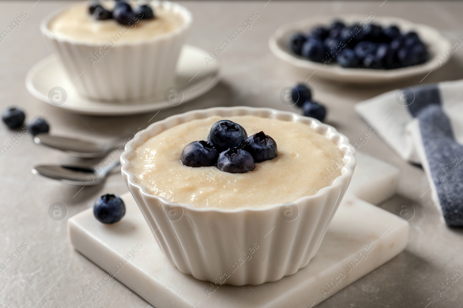 Photo of Delicious semolina pudding with blueberries on white table