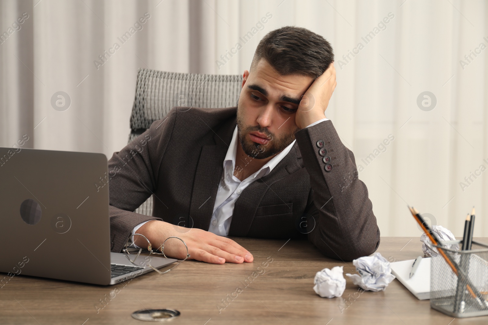 Photo of Tired sad businessman sitting at table in office