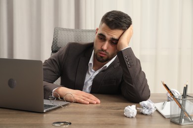 Photo of Tired sad businessman sitting at table in office