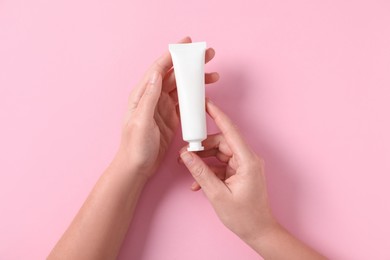 Photo of Woman with tube of hand cream on pink background, top view