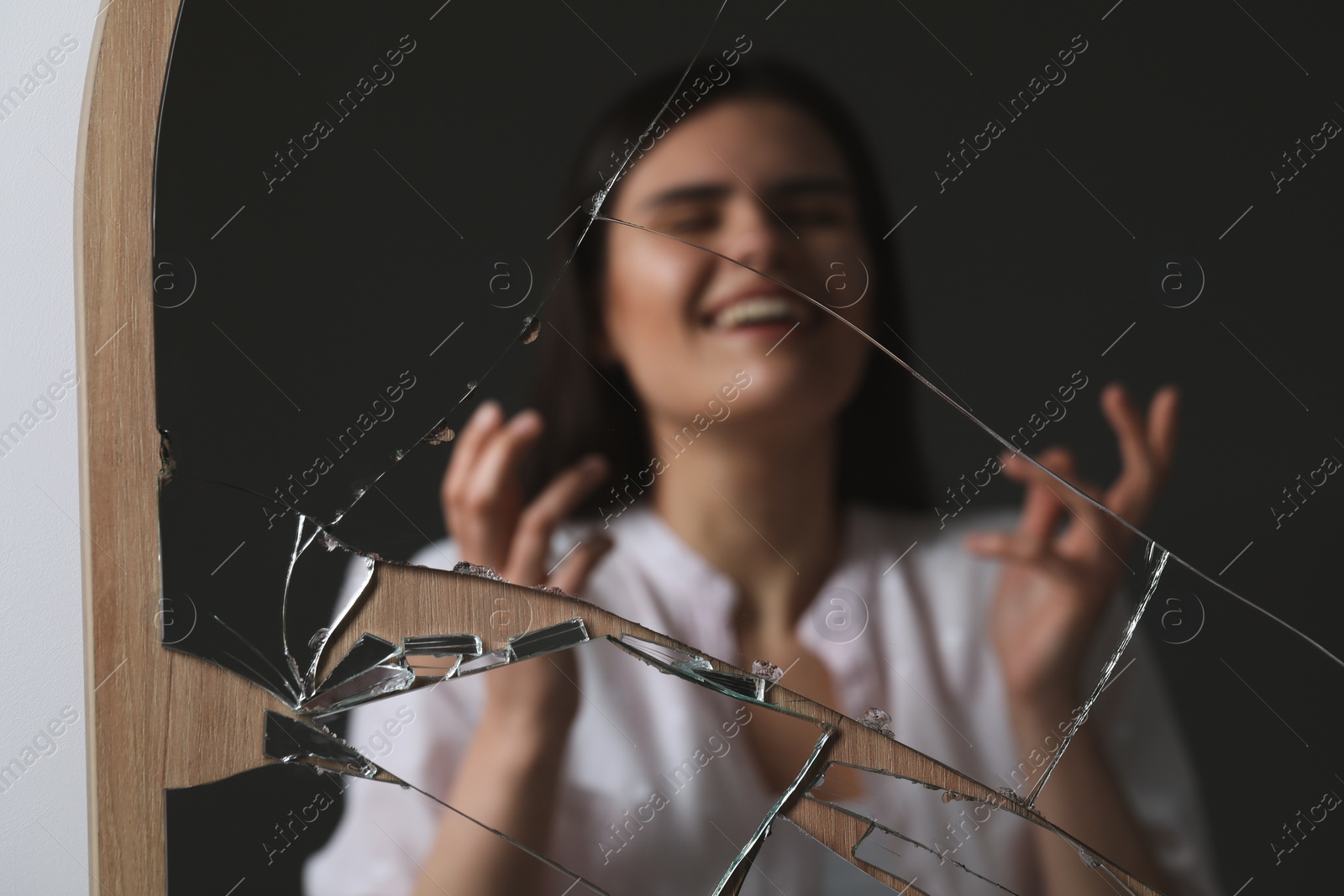Photo of Blurred reflection of smiling woman in broken mirror