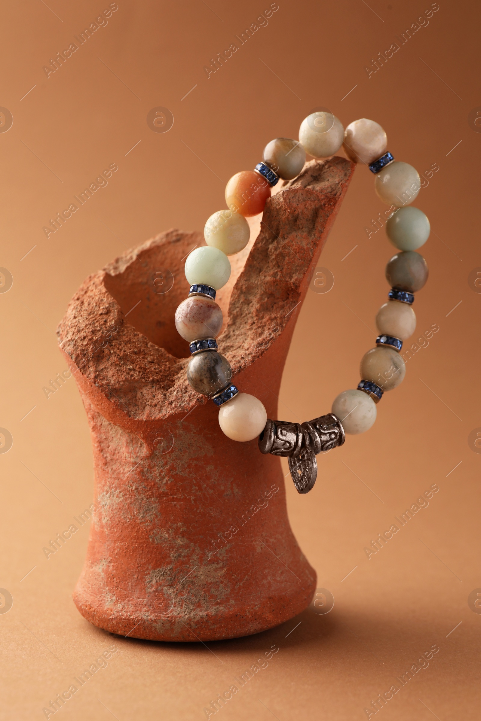 Photo of Stylish presentation of beautiful bracelet with gemstones on light brown background