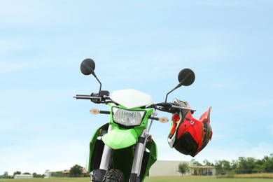 Photo of Stylish green cross motorcycle with helmet outdoors