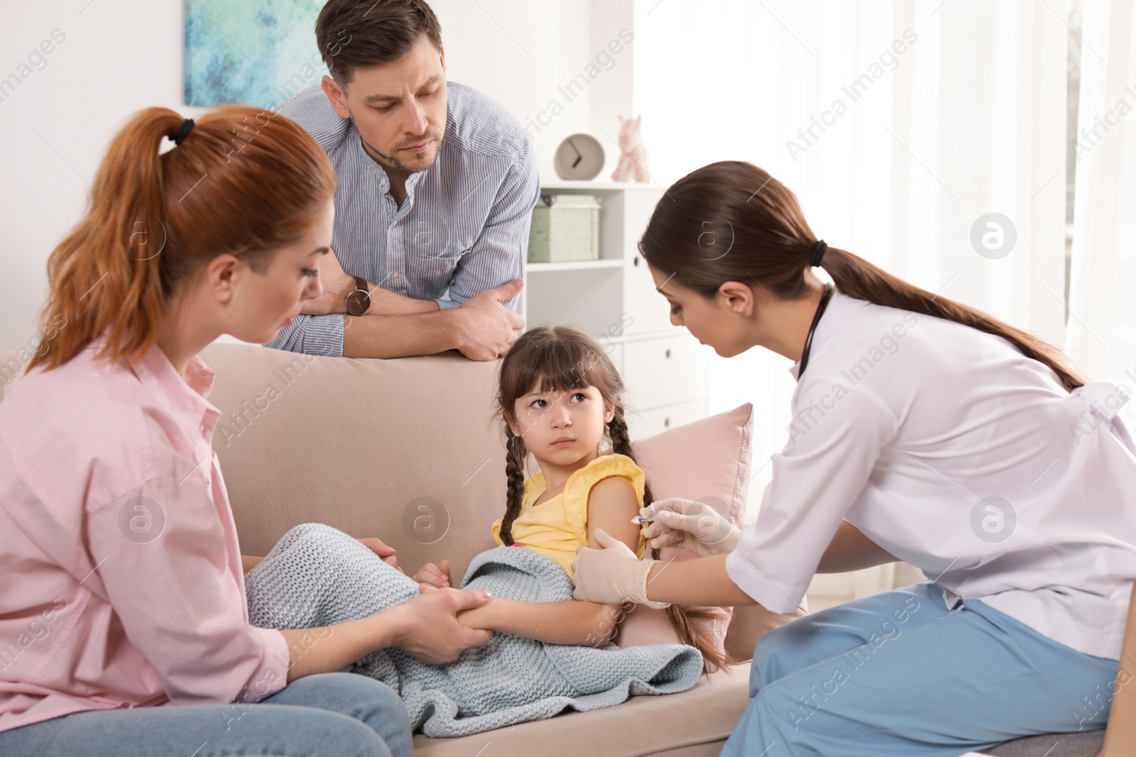 Photo of Family doctor vaccinating little child at home