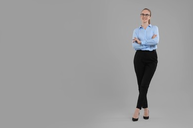 Photo of Happy young secretary with crossed arms on grey background, space for text