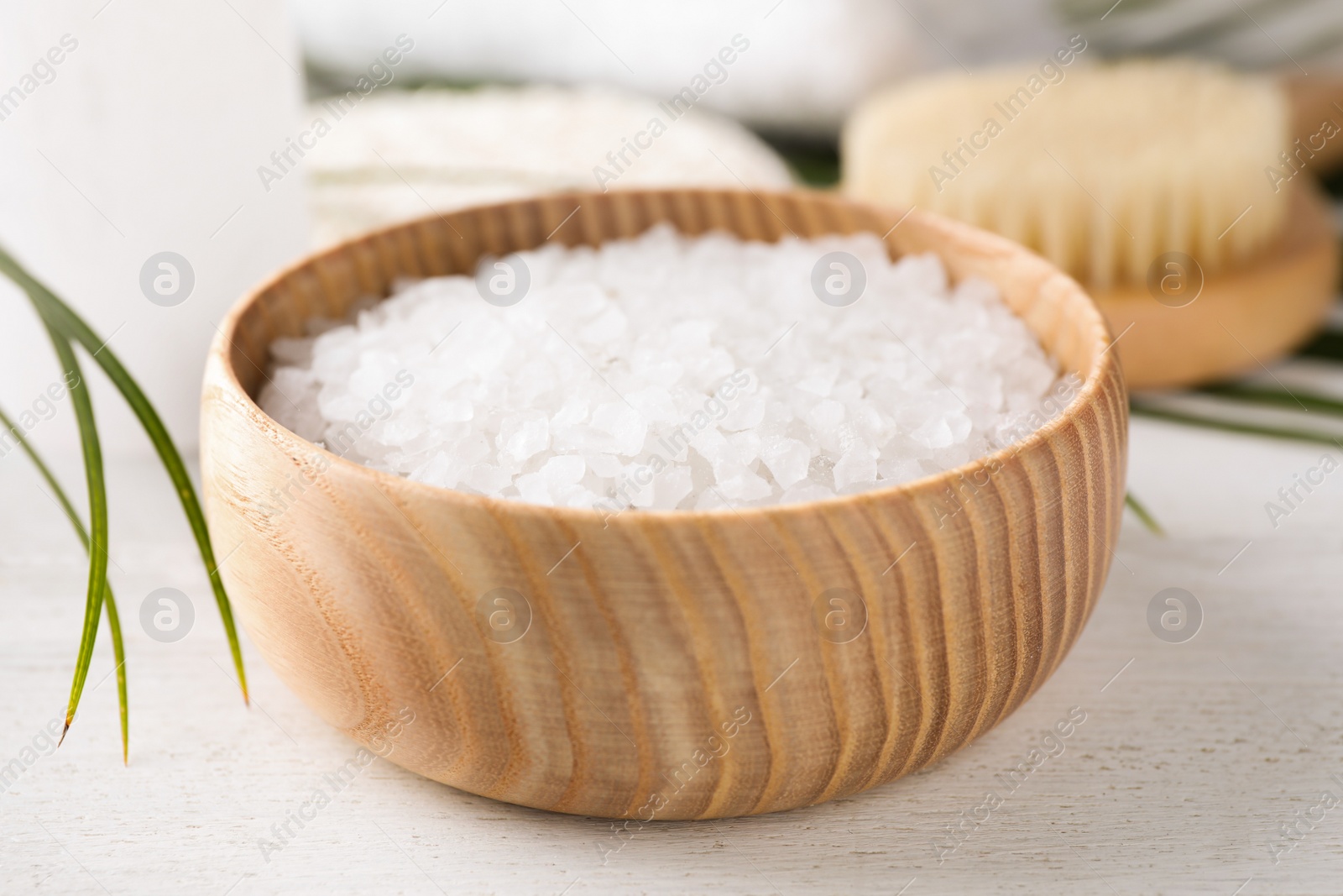 Photo of White sea salt for spa scrubbing procedure on wooden table