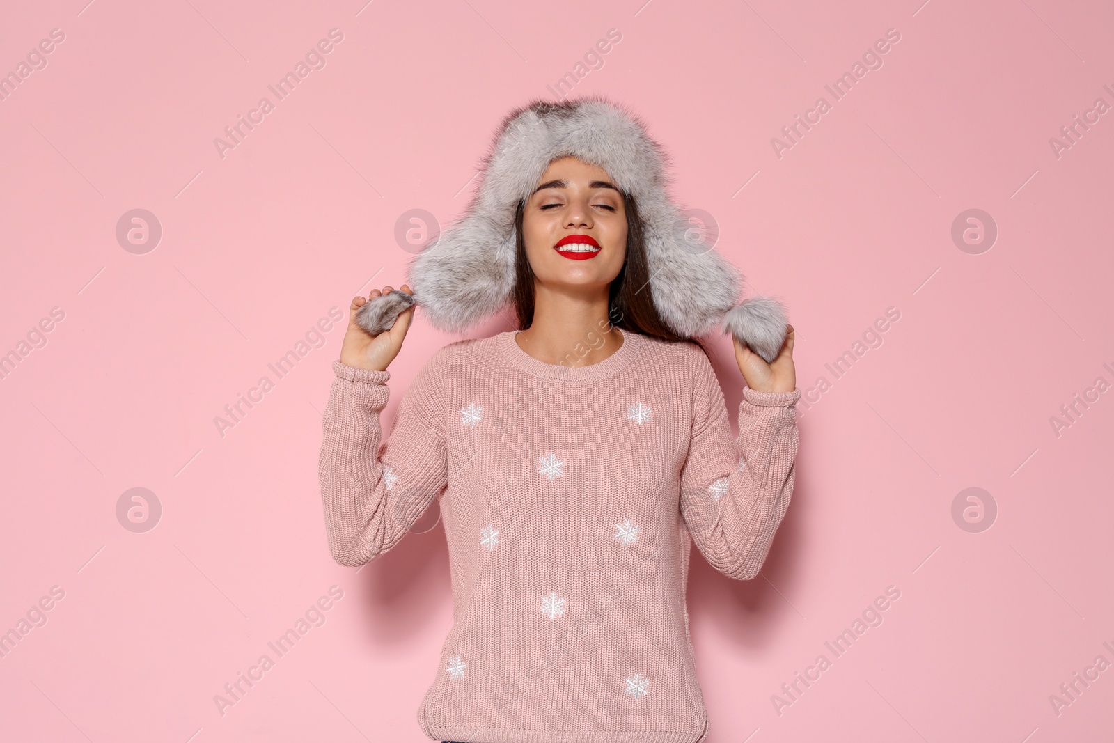 Photo of Young woman in warm sweater and hat on color background. Celebrating Christmas