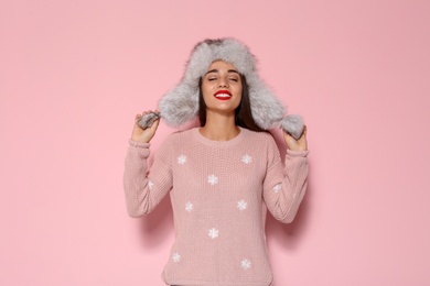 Photo of Young woman in warm sweater and hat on color background. Celebrating Christmas