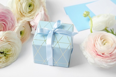 Photo of Beautiful ranunculus flowers, gift box and envelope on white background