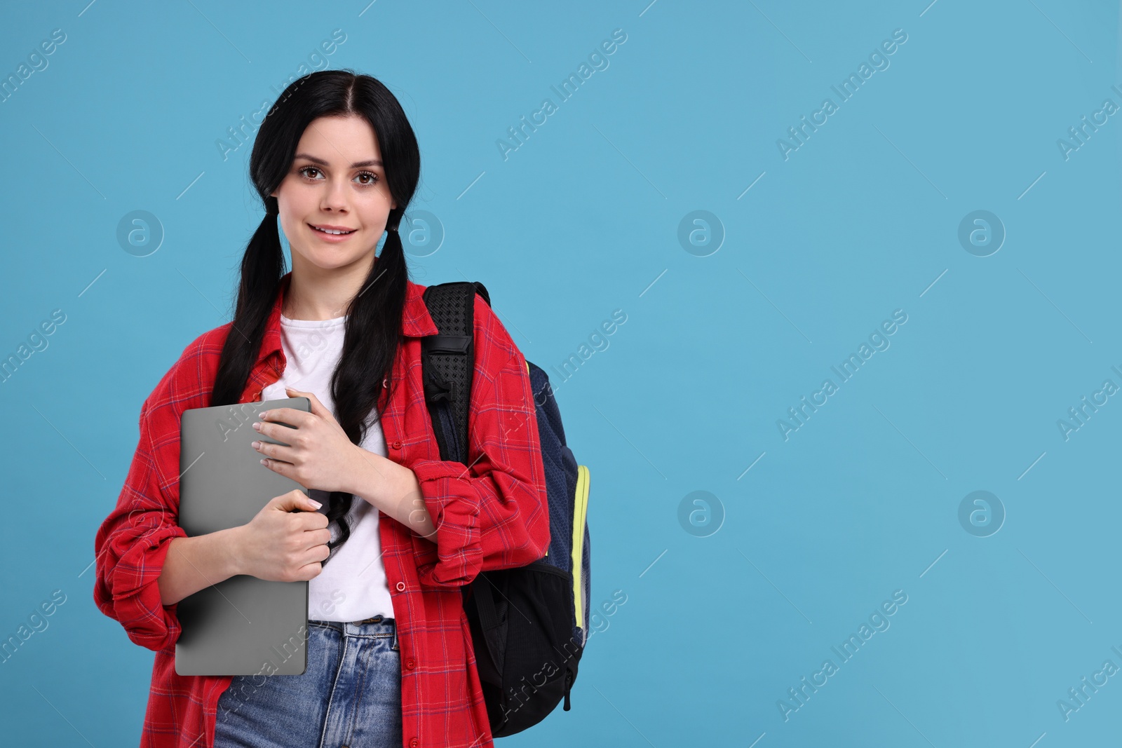 Photo of Smiling student with laptop on light blue background. Space for text